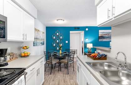 A kitchen with a blue wall and white cabinets.