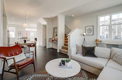 A living room with a white couch and a wooden chair.