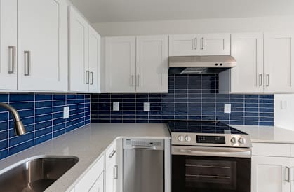 A kitchen with white cabinets and a blue tile backsplash.