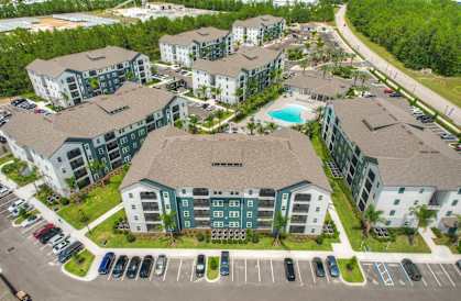 an aerial view of an apartment complex with a swimming pool and parking lot at Fountainhead, Jacksonville, 32258