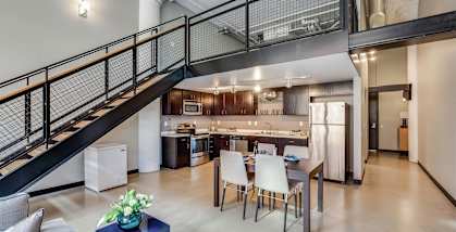 A modern open concept living space with a kitchen in the background.