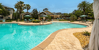 Swimming pool surrounded by palm trees and lounge chairs at Bridges at Crosstown Apartments in Tampa, FL