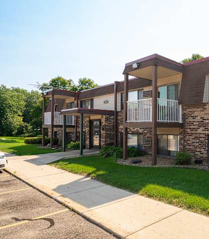 an exterior view of a brick apartment building with a sidewalk