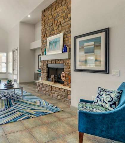 Clubhouse Seating Area with Large Windows and Natural Light Blue Couches and Armchairs  Around Fireplace