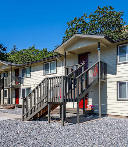 A two-story house with a red door and a balcony.