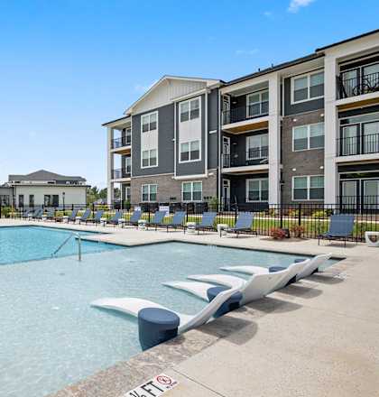 A large swimming pool in front of apartment buildings.