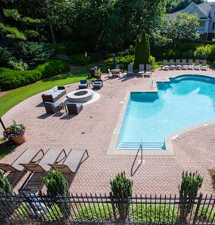a swimming pool with lounge chairs and trees in the background