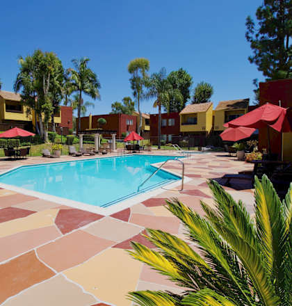 a swimming pool in the middle of a hotel courtyard with umbrellas at Brookhollow Apartments, West Covina , California