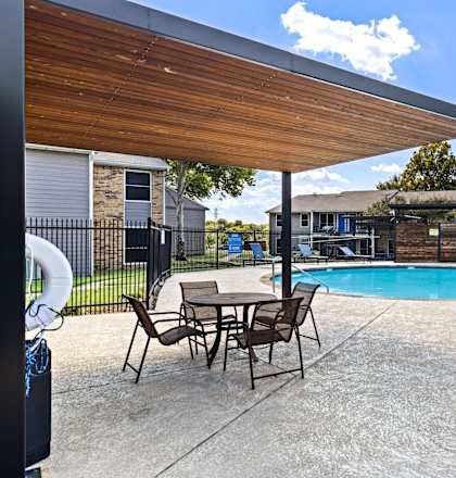A patio with a table and chairs and a pool.