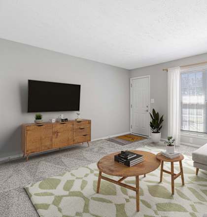 A living room with a grey couch, a wooden coffee table, a flat screen TV, and a green plant.