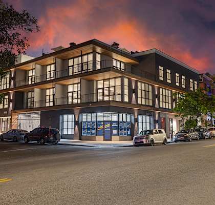 a rendering of a building on a street with a sunset in the background