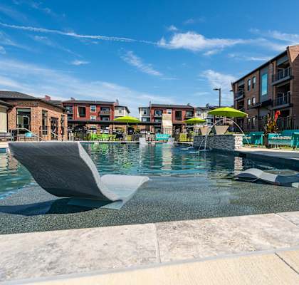 a swimming pool with chairs and umbrellas in front of apartment buildings