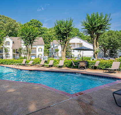 a swimming pool with chairs around it and houses in the background
