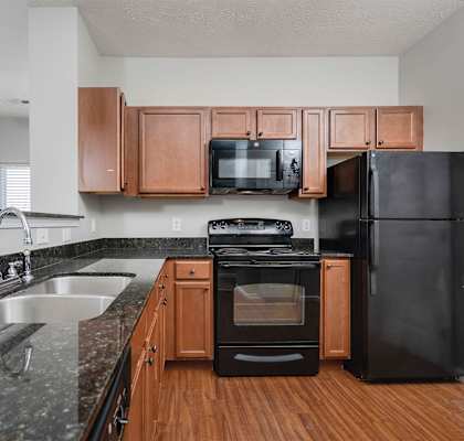 A black refrigerator sits next to a black oven in a kitchen.