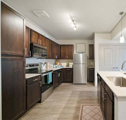 a kitchen with dark wood cabinets and white countertops