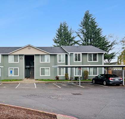 A large grey building with a parking lot in front.