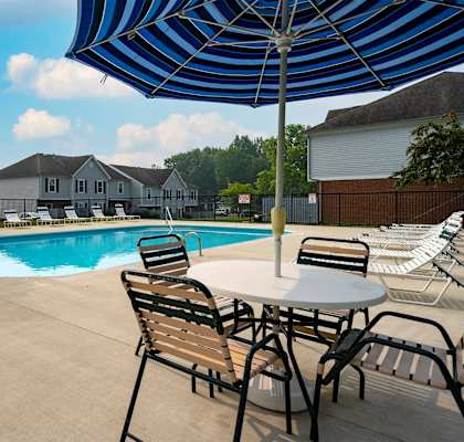 A pool with chairs and an umbrella in the foreground.