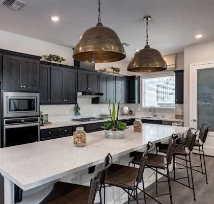 A modern kitchen with a white island and black cabinets.  at Heritage Landing Apartments, Chico, California