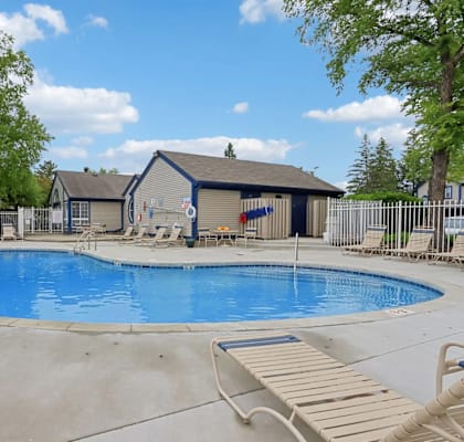 A small pool with a deck and a house in the background.