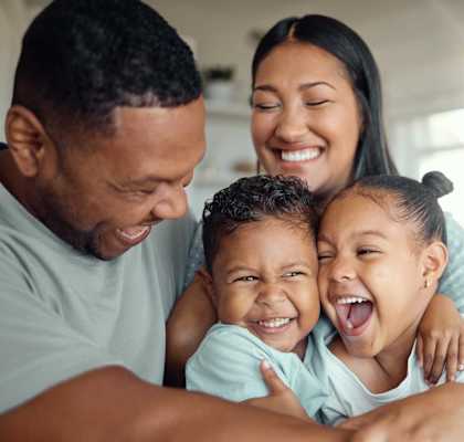 A family of three is hugging and smiling together.