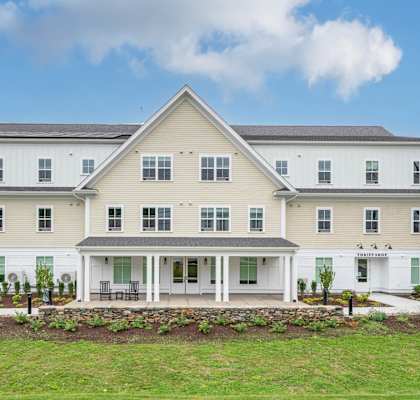 A large white house with a grey roof and a porch.