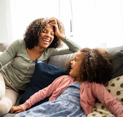 A woman and a girl are sitting on a couch.