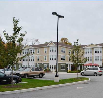 Apartment complex with a parking lot in front.