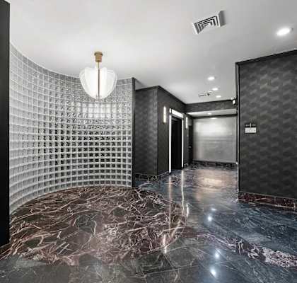 A hallway with a marble floor and a wall covered in a grid-like pattern.