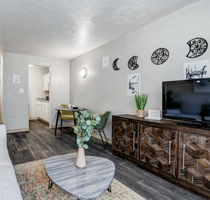 A living room with a grey sofa, a grey coffee table, a wooden cabinet, and a TV.