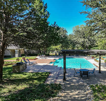 a resort-inspired swimming pool surrounded by lush landscaping at Stoneleigh on Spring Creek apartments