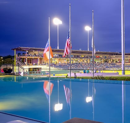 a view of a swimming pool flags and a stadium in the background