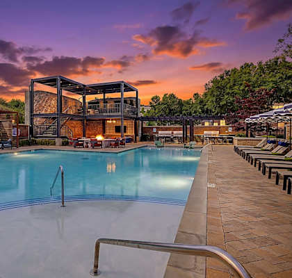 A large outdoor swimming pool with a metal ladder and a building in the background.