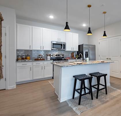 a kitchen with white cabinets and a large island with two stools