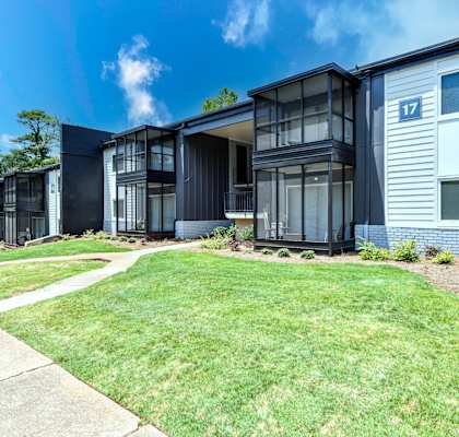 a group of houses in a row with a grassy area and trees in the background
