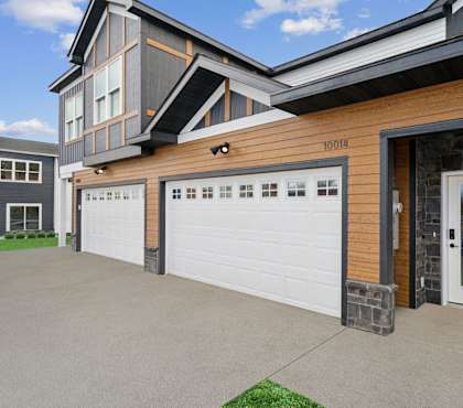 A modern house with a garage door and a stone wall.