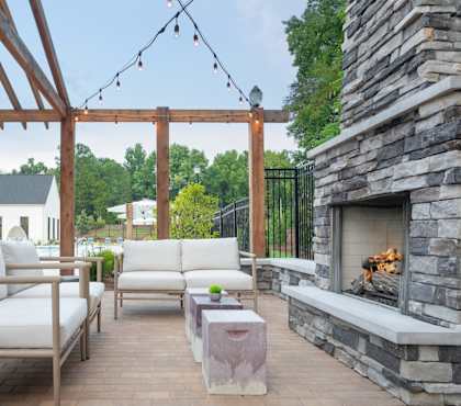 A patio with a fireplace and white furniture.
