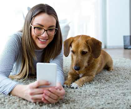 a woman laying on the floor with her dog looking at a cell phone Pineview Apartments in Clearwater, FL 33755