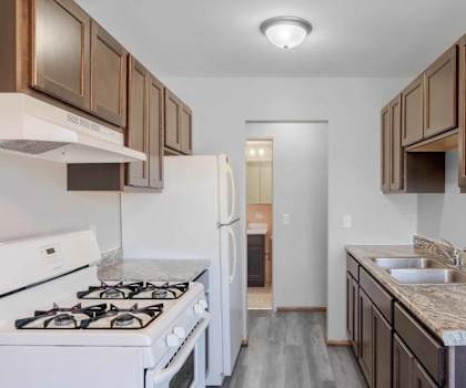 A kitchen with a white stove and a sink with a marble countertop.