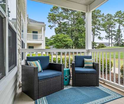 Two chairs and a table on a porch.