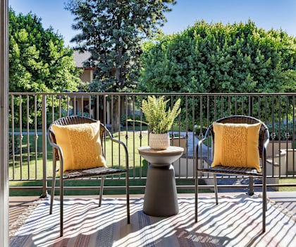 Two chairs with yellow pillows sit on a patio.