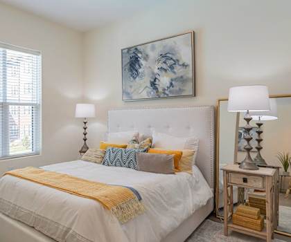 A bedroom with a large bed and a painting on the wall.