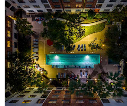 an aerial, night-time view of the swimming pool at The Core apartments