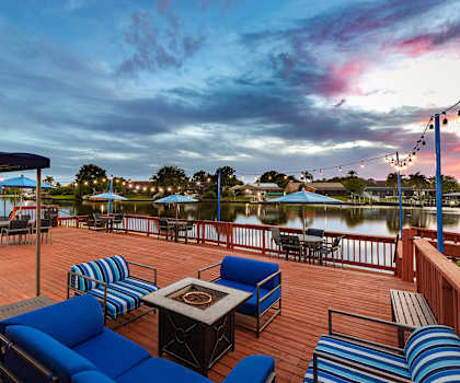 a deck with blue couches and chairs overlooking a body of water