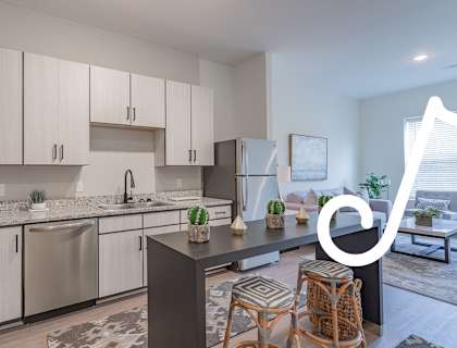 a kitchen with a large island with stools and a couch in the background