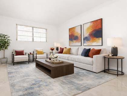 A living room with a white couch, a coffee table, and two paintings on the wall.