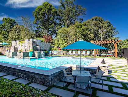a swimming pool with a waterfall and patio furniture