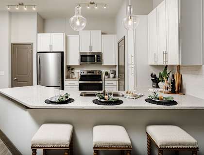 A modern kitchen with a large island and stools.