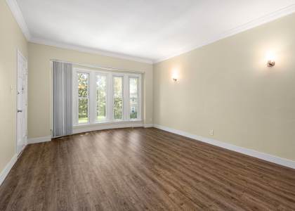 an empty living room with wood floors and a window
