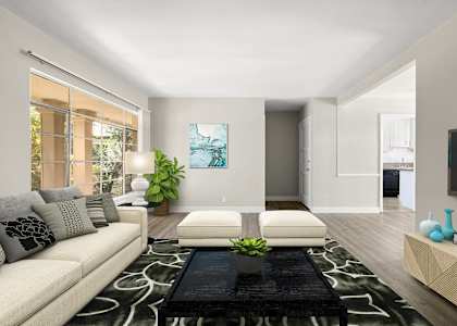 A living room with a white couch, a black and white rug, and a painting on the wall.