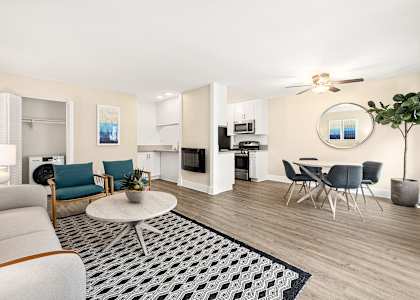 a living room with a couch table and chairs and a kitchen with a stove and microwave